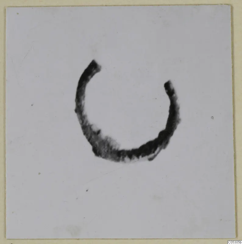 Open ring of bronze, a piece of personal adornment, photographed alone on a pale ground.