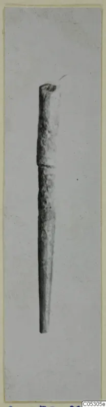 Bone pin, a long slender pin tapering to a point, photographed upright on a grey background