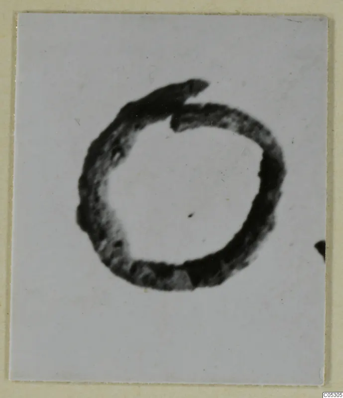 Close photograph of a bronze ring-shaped personal adornment from Lapithos on a pale background