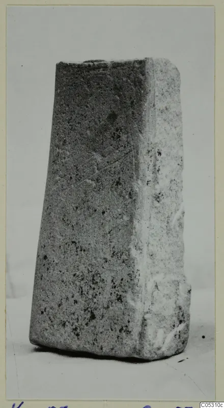 Tapered stone block from Kythrea, standing alone on a pale surface against a plain background