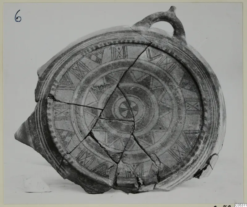 Pottery Bichrome II vessel with a loop handle, reassembled from broken sherds and painted with patterned bands