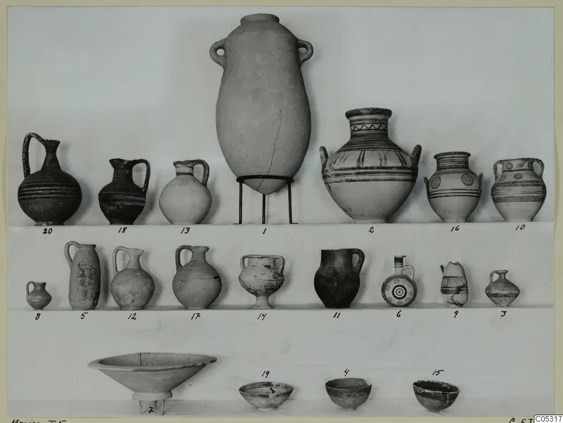 Twenty numbered pottery vessels, jugs, jars and bowls, set out in three rows against a plain backdrop