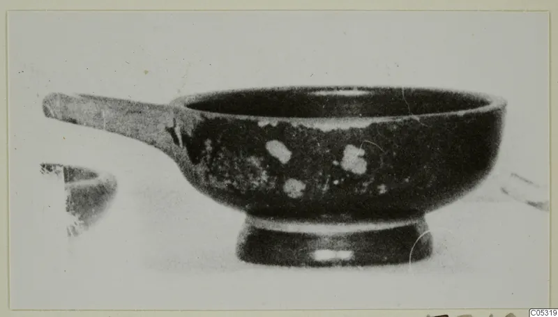 Black-glazed bowl with a long horizontal handle and a ring foot, seen from the side, from Marion tombs 31–45 finds