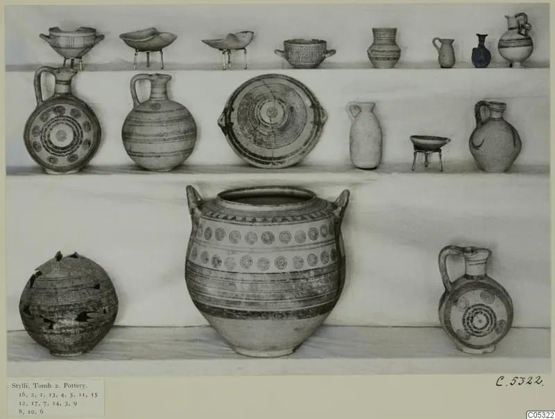 Group of pottery vessels from Stylli, Tomb 2, arranged on shelves against a plain backdrop
