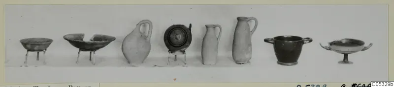 Eight vessels from Tomb 49 at Marion lined up in a row against a plain background, bowls, jugs and cups.