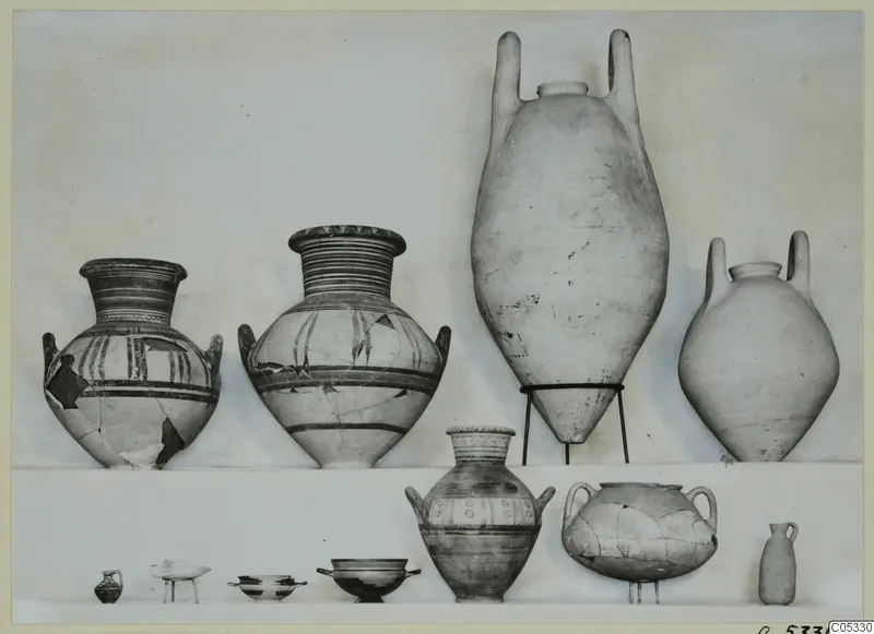 Pottery jars and small vessels from Marion, Tombs 96 and 8, set out for photographing in two rows.