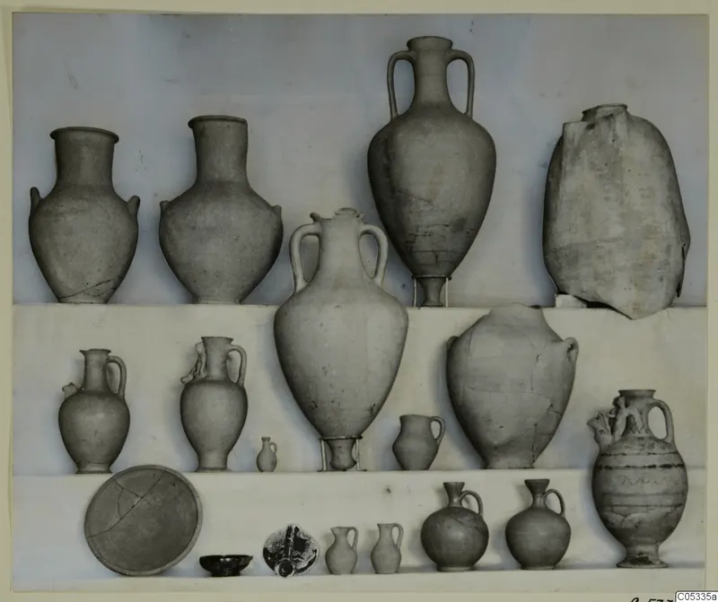Group of pottery vessels from Tomb 52 at Marion, arranged in three rows: jugs, two-handled amphorae, jars and small bowls.