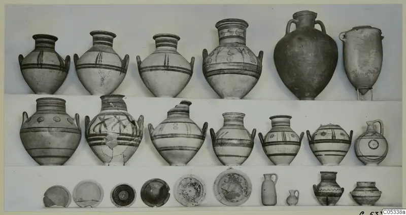 Rows of painted jars, bowls and small vessels from Marion, Tomb 84, photographed on a light background.