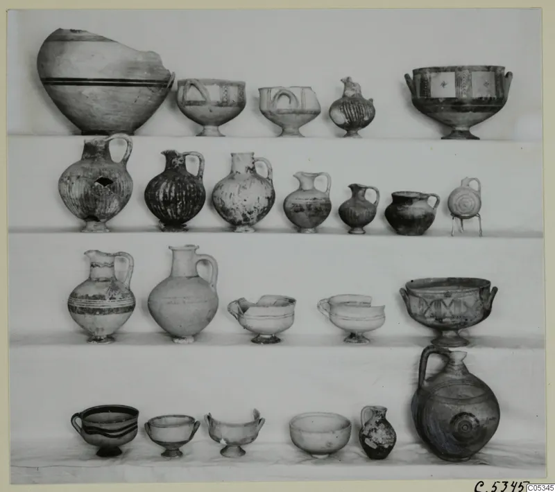 Pottery from Tomb 63 at Marion: about twenty vessels, jugs, bowls and juglets, set out in four rows.