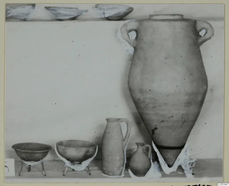 Pots and bowls from Tomb 35 at Marion, set out on a shelf against a plain pale background.