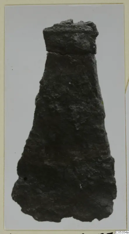 Corroded iron tool, tapering from a squared top to a wide, irregular lower end
