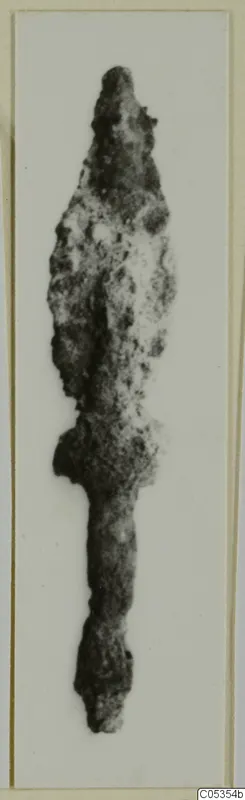 Corroded iron spearhead with a pointed blade and long tang, shown alone against a white background.