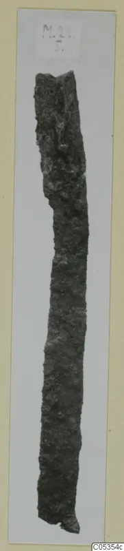Corroded iron knife, long and narrow, photographed upright on a light card mount