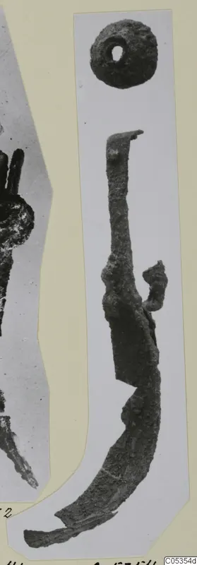 Corroded iron strigil and a small round object with a hole, from Marion tomb finds