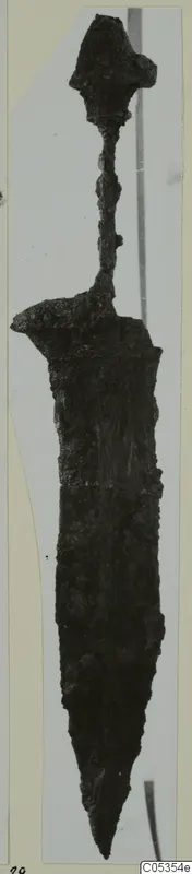 Iron weapon with a pointed blade, a narrow grip and a flared knob-shaped top, photographed upright against a grey background.