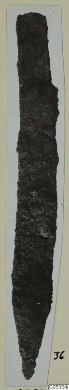 Corroded iron knife blade from Marion, Tomb 39, photographed upright on a mounted card.