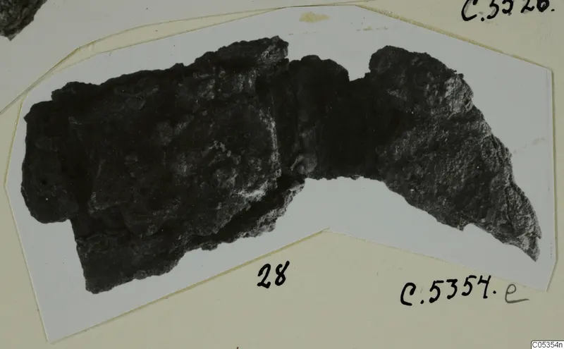 Corroded iron object from Marion, shown on a white card mount with handwritten number labels