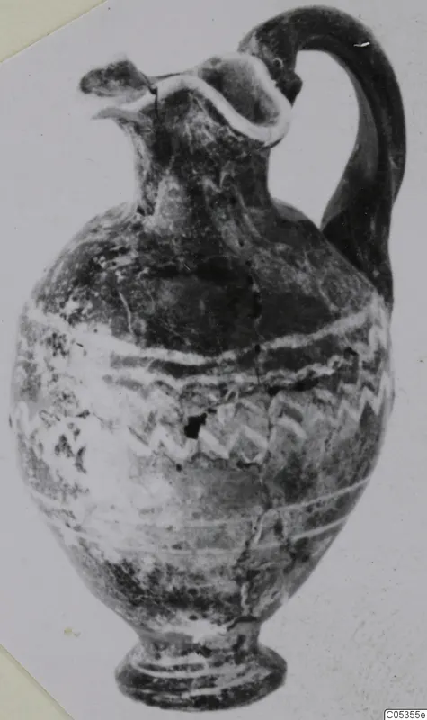 Sand-core glass jug with a tall curved handle and white wavy trails on its body