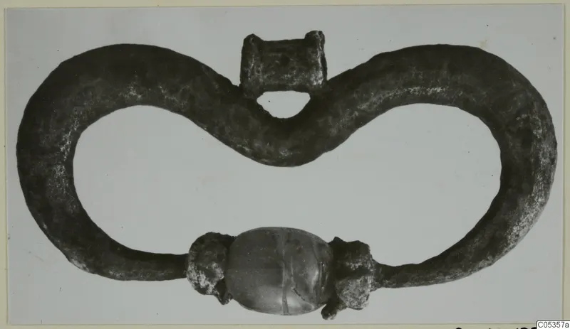 Dark metal loop with a barrel-shaped bead at its lower centre, from Marion
