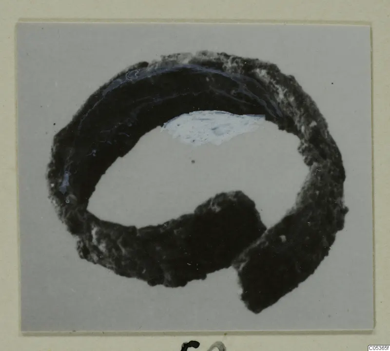 Corroded bronze ring-shaped adornment from Amathus, shown on a grey background with a cream mount.