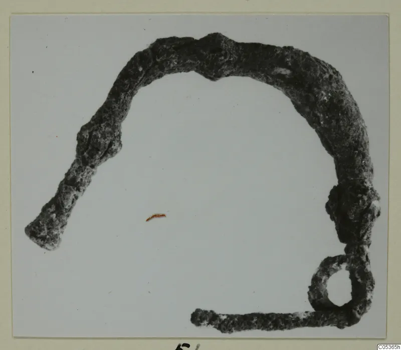 Corroded bronze personal adornment from Amathus, a bent bar with a loop at one end.