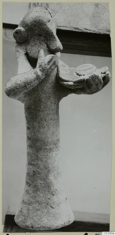 Figurine of a standing figure with one hand raised to its face and the other arm holding a flat dish-like form