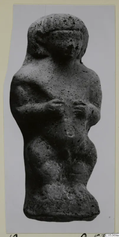 Small standing figure from Amathus, grey and pitted, with arms bent across the chest and a rounded head