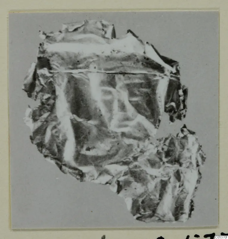 Crumpled fragment of thin sheet with a faint impressed pattern, from Amathus, shown on a grey backing.