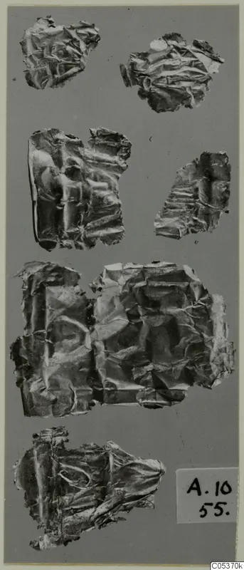 Several crumpled gold foil fragments from Amathus, tombs 10–26, laid out on a grey background.