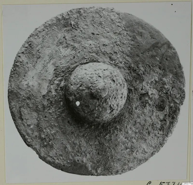 Round object with a central domed boss pierced by a small hole, from Amathus.