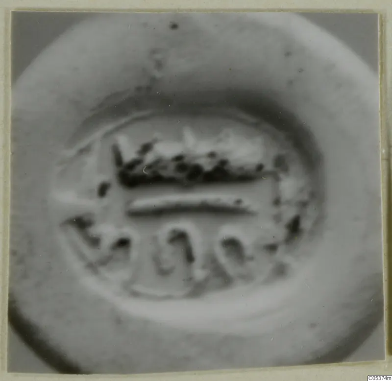 Blurred close-up of an engraved seal or gem face with a horizontal band and looped motifs