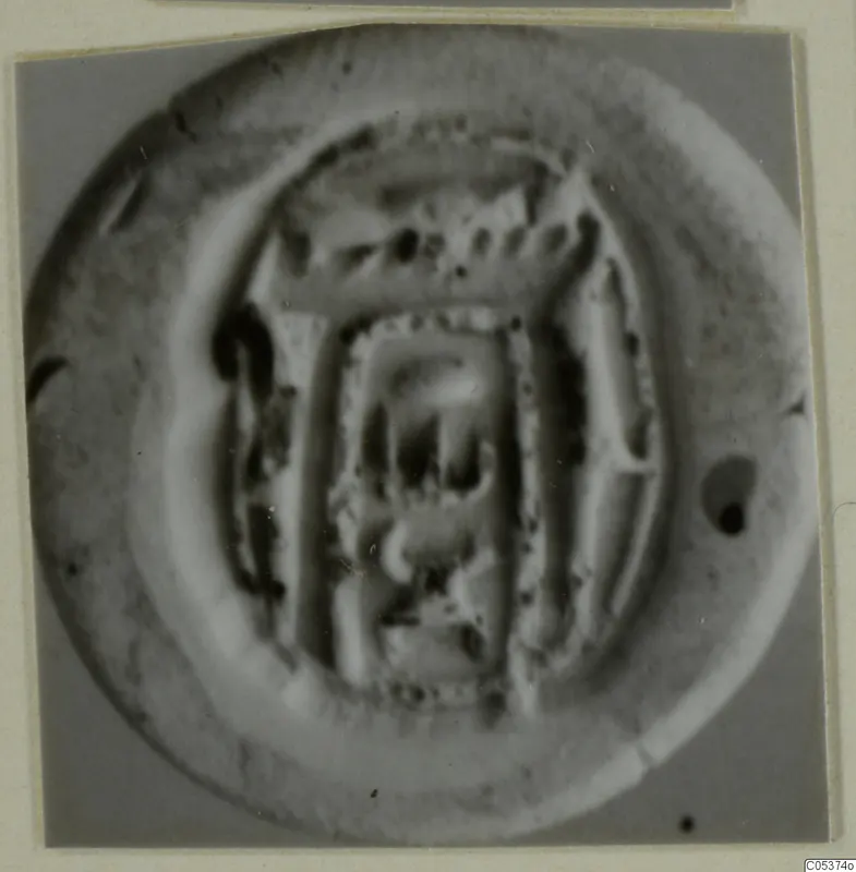 Round seal or impression with a raised rim and a rectangular design in the centre, photographed close up.
