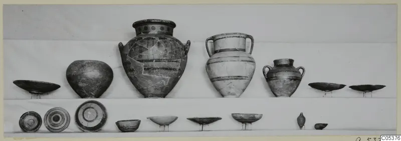 Pottery vessels from Amathus, Tomb 2, set out in two rows on shelves against a plain backdrop