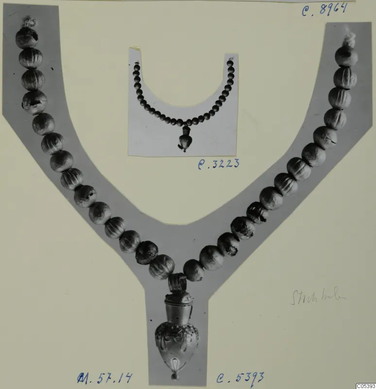 Two photographs of bead necklaces with pendants, mounted on grey and white card, one with a gold-coloured pendant at the lower point.