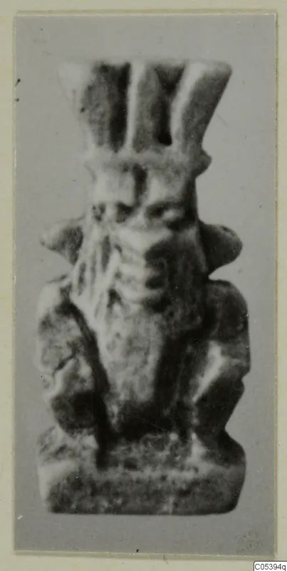 Small figure amulet from Marion, Tomb 50, photographed against a grey backdrop