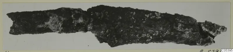 Corroded iron tool fragment from Amathus, shown lying horizontally on a pale background