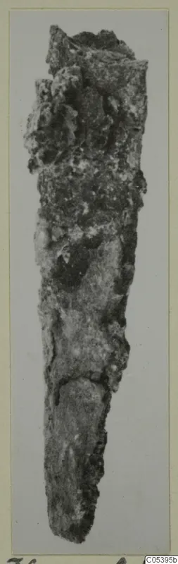 Corroded iron tool from Amathus, long and tapering to a point, photographed upright on a mounted card