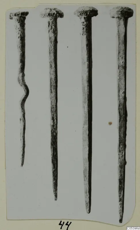 Four corroded metal nails from Marion, photographed upright side by side on a card mount.