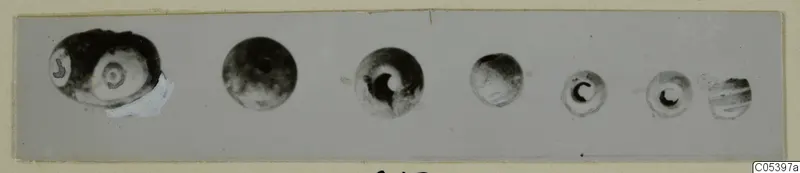 Row of seven beads from Marion Tomb 9, the largest at left with concentric rings like an eye.