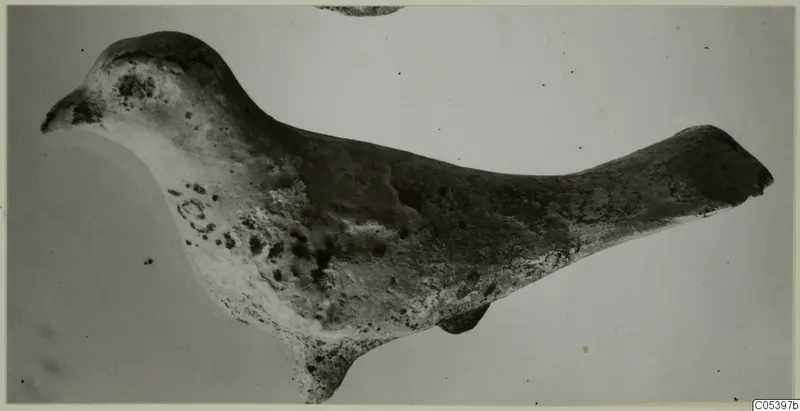 Terracotta figurine of a bird in side view, head to the left and a long tapering tail to the right, worn surface