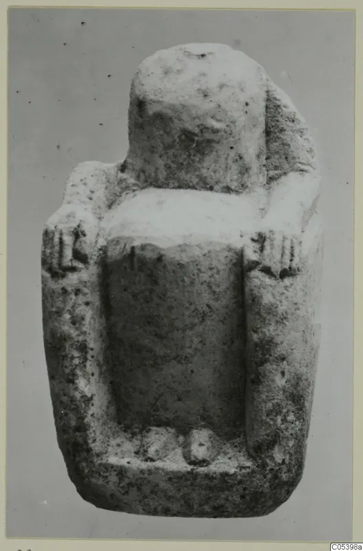 Limestone figurine of a seated figure with a blocky head and short arms, against a plain grey background.