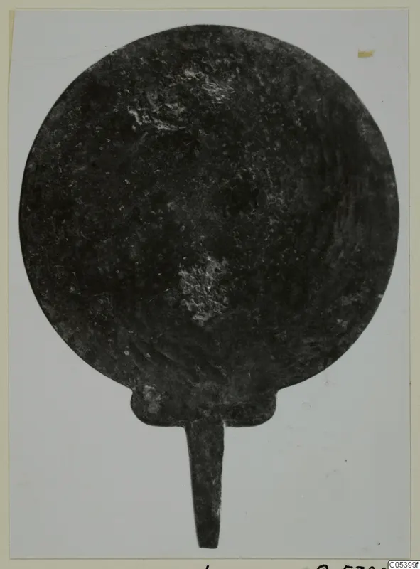 Round metal disc with a short tang from Marion Tomb 38, dark and corroded