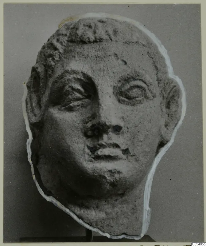Sculpted head with short hair, large heavy-lidded eyes and a chipped nose, pale stone, on a dark stand, from Mersinaki