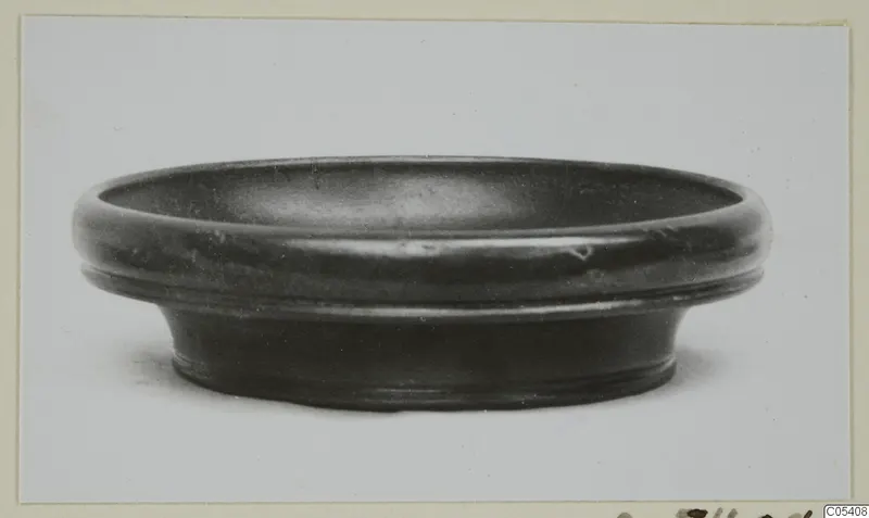 Pottery Black Glazed Ware bowl with a thick rounded rim and flaring foot, seen from the side