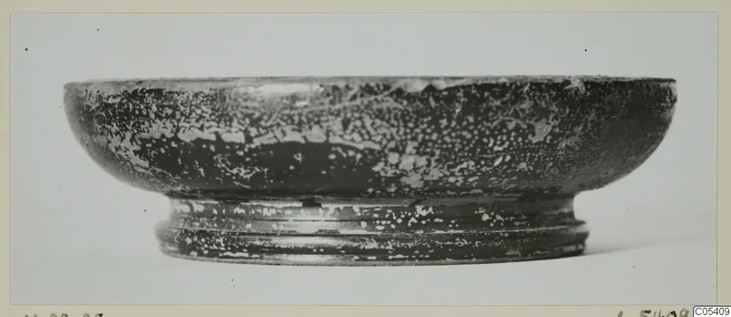 Black glazed pottery bowl with a low ring foot, seen from the side
