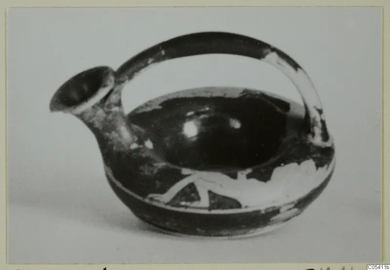 Small spouted vessel with a loop handle, dark glaze and pale painted pattern on the body
