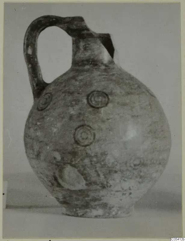 Pottery Black-on-Red jug with a single loop handle and concentric circle motifs on its round body