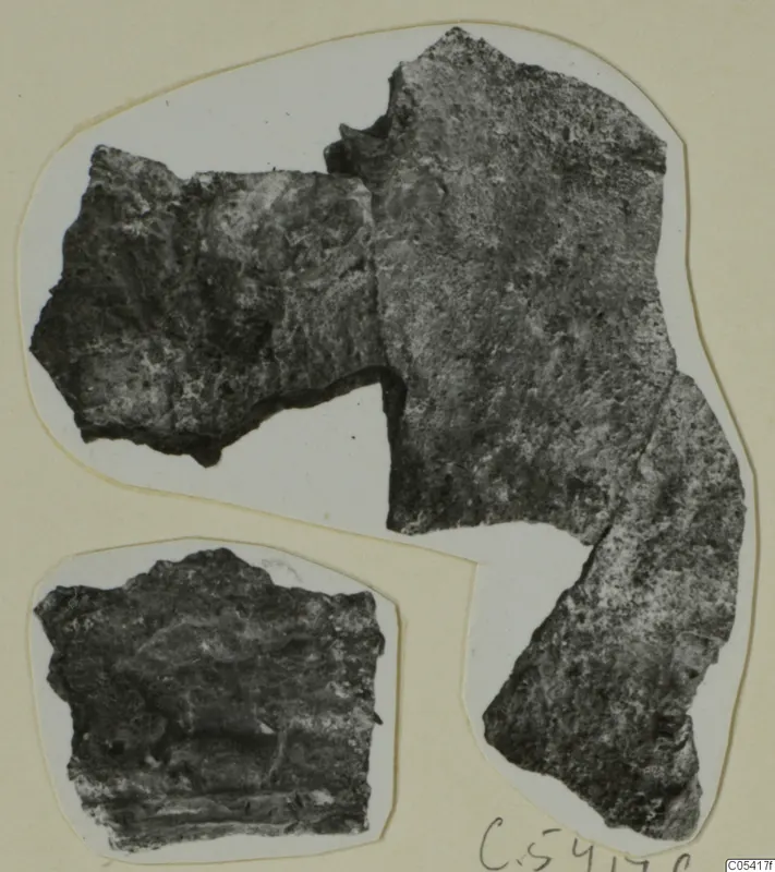 Two corroded metal fragments from Amathus, photographed on a white card mount.
