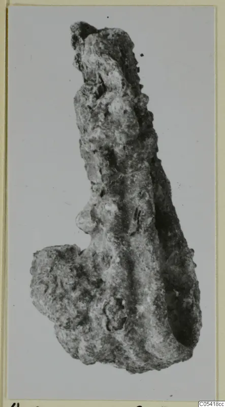 Heavily corroded iron object, long and narrow, from Amathus, shown against a pale background