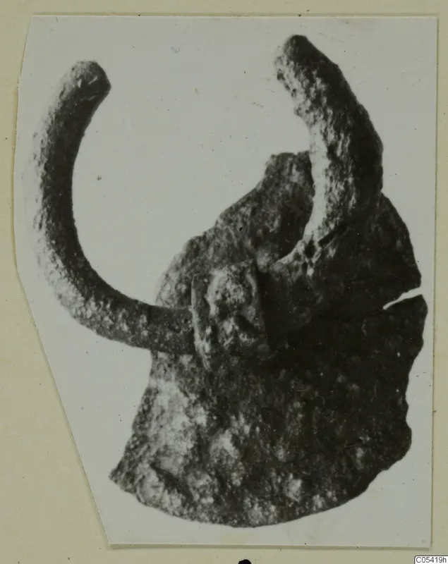 Corroded metal fragment from Marion Tomb 58: a curved arm joined to a flat, broken plate.